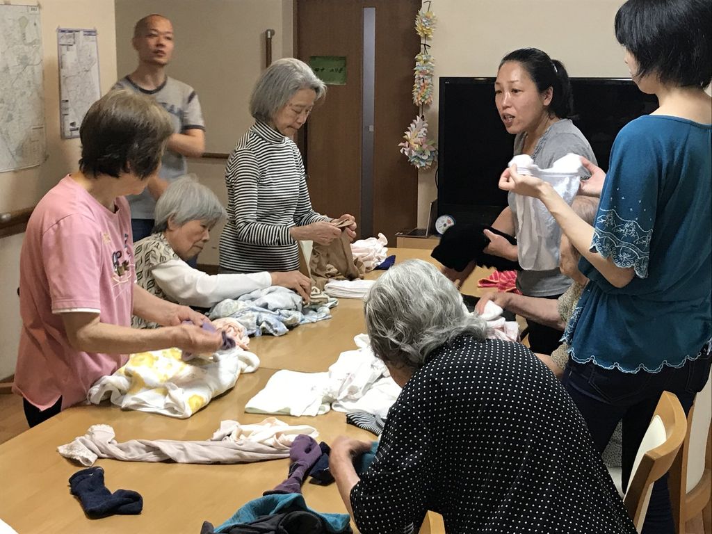 入居者さんとスタッフが、テーブルを囲んで洗濯物をたたんでいます